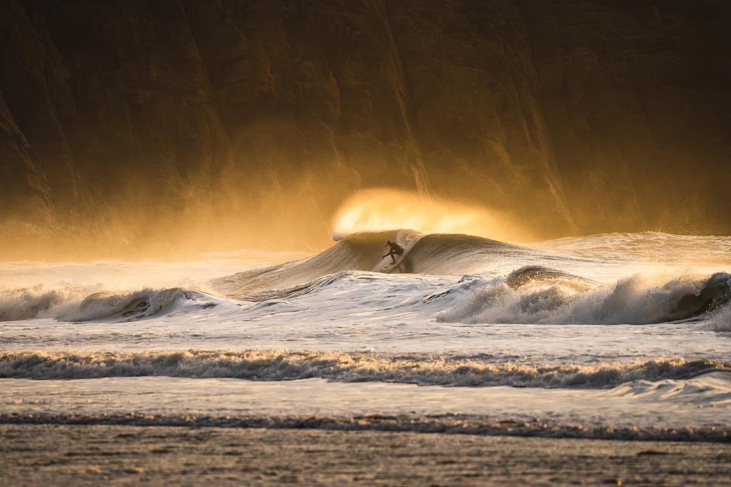 surfer in northwales surfing a wave at north ceiriad at sunrise